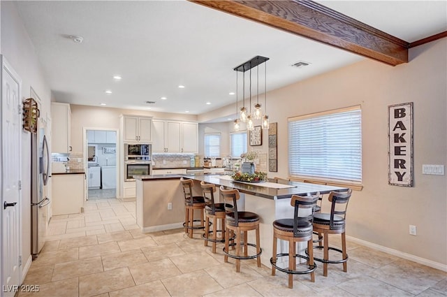 6821 Jeanette St, Las Vegas, NV 89131 - kitchen with appliances with stainless steel finishes, tasteful backsplash, a breakfast bar area, a spacious island, and white cabinets