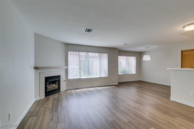 350 S Durango Dr Unit 103, Las Vegas, NV 89145 - unfurnished living room featuring wood finished floors, a tile fireplace, and baseboards