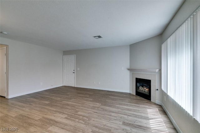350 S Durango Dr Unit 103, Las Vegas, NV 89145 - unfurnished living room with light wood finished floors, a tiled fireplace, and baseboards