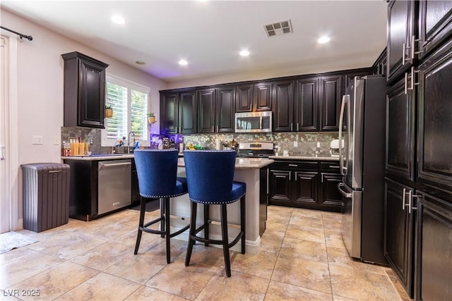 10526 Harvest Wind Dr, Las Vegas, NV 89135 - kitchen with appliances with stainless steel finishes, decorative backsplash, a kitchen island, a kitchen bar, and recessed lighting