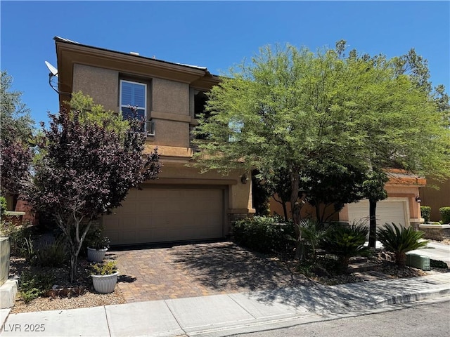 10526 Harvest Wind Dr, Las Vegas, NV 89135 - obstructed view of property with a garage, stucco siding, and decorative driveway