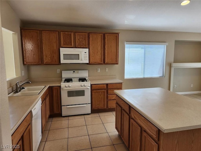 5605 Midnight Breeze St, North Las Vegas, NV 89081 - kitchen with white appliances, brown cabinetry, light countertops, light tile patterned floors, and a kitchen island