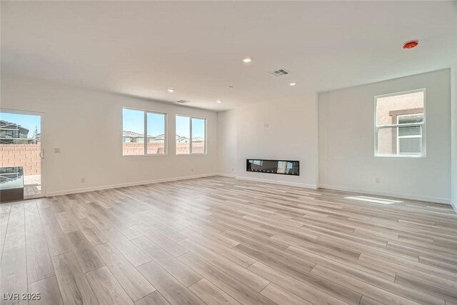 9842 Lost Horse Ave, Las Vegas, NV 89178 - unfurnished living room with light wood finished floors, a glass covered fireplace, baseboards, and recessed lighting