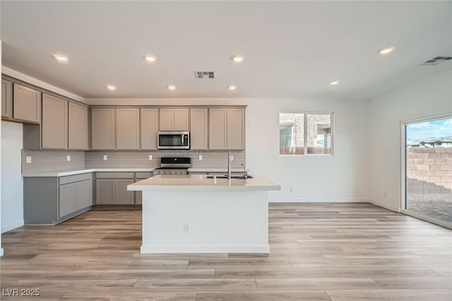 9842 Lost Horse Ave, Las Vegas, NV 89178 - kitchen with stainless steel appliances, gray cabinets, a sink, decorative backsplash, and light wood-type flooring
