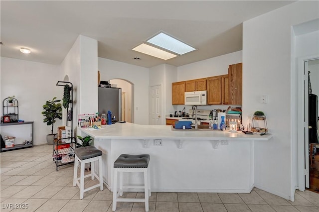 7616 Yondering Ave, Las Vegas, NV 89131 - kitchen with white appliances, brown cabinets, a breakfast bar area, and a peninsula