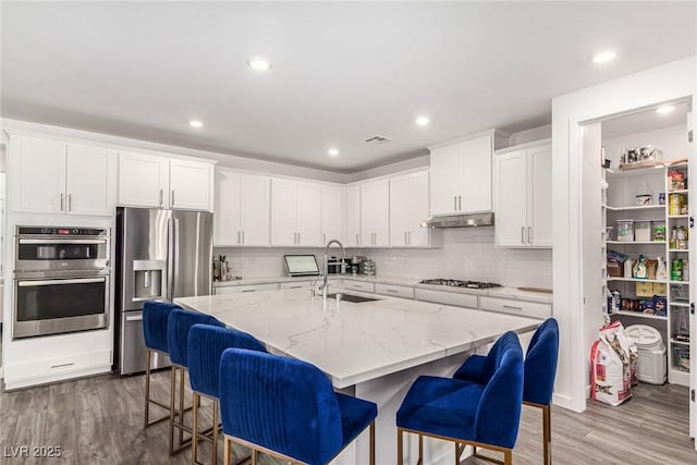 12332 Switchgrass Ave, Las Vegas, NV 89138 - kitchen with stainless steel appliances, a sink, wood finished floors, white cabinets, and recessed lighting