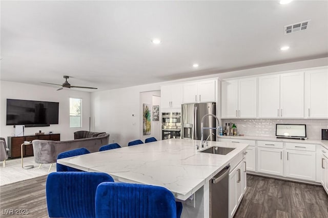 12332 Switchgrass Ave, Las Vegas, NV 89138 - kitchen with a sink, appliances with stainless steel finishes, dark wood-style flooring, a kitchen island with sink, and light stone counters