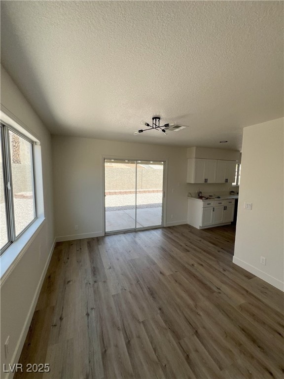 8068 Cetus Cir, Las Vegas, NV 89128 - unfurnished living room featuring a textured ceiling, wood finished floors, and baseboards