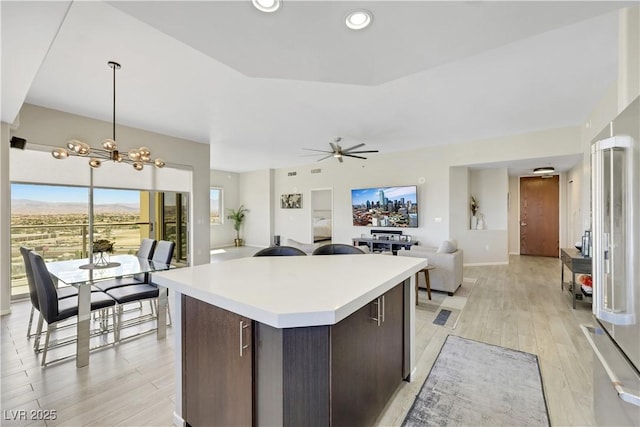 8255 Las Vegas Blvd Unit 1821, Las Vegas, NV 89123 - kitchen with dark brown cabinetry, light countertops, a center island, light wood-style flooring, and a chandelier