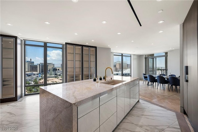 1 Hughes Center Dr Unit 1901, Las Vegas, NV 89169 - kitchen featuring a sink, modern cabinets, expansive windows, a large island with sink, and light stone counters