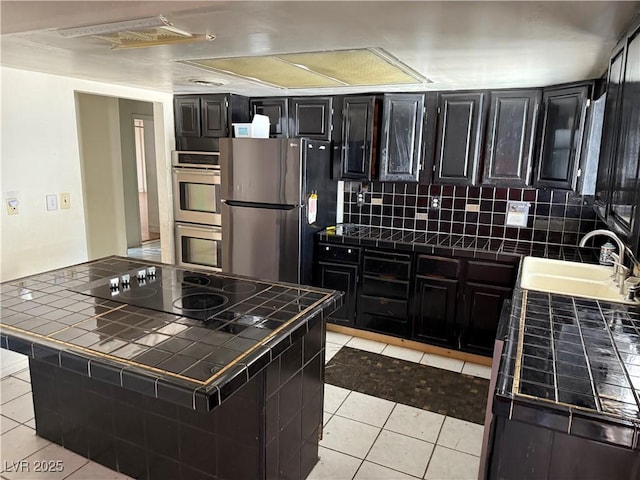 1674 Seneca Ln, Las Vegas, NV 89169 - kitchen featuring tile countertops, stainless steel appliances, a sink, and light tile patterned floors