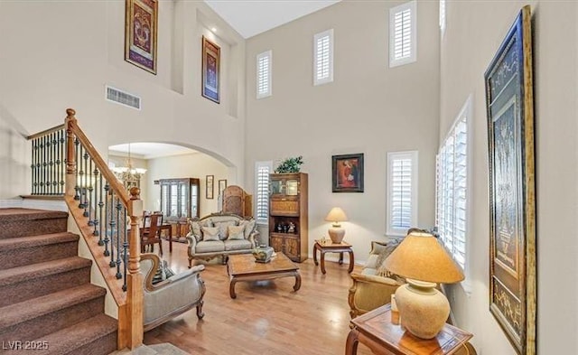 10001 Blairwood Ct, Las Vegas, NV 89178 - living room with arched walkways, a chandelier, wood finished floors, a towering ceiling, and stairs