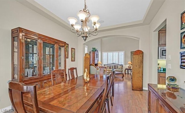 10001 Blairwood Ct, Las Vegas, NV 89178 - dining space with arched walkways, a chandelier, and light wood finished floors