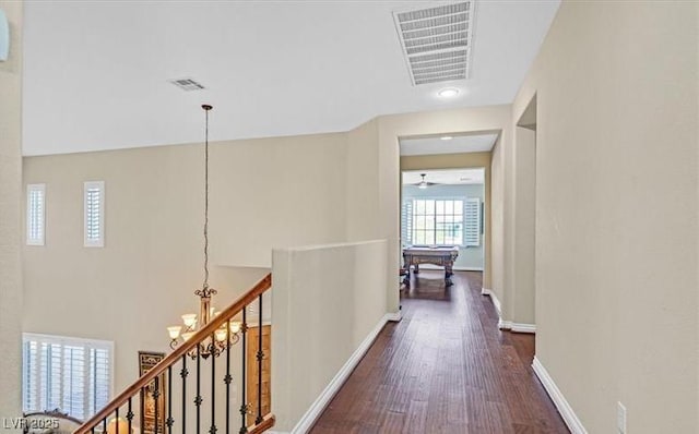 10001 Blairwood Ct, Las Vegas, NV 89178 - hallway featuring dark wood-style flooring, a chandelier, an upstairs landing, and baseboards