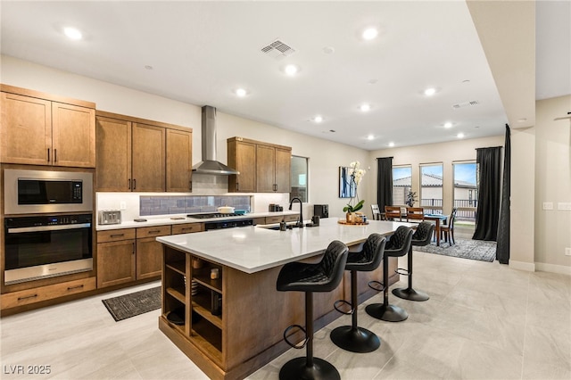 230 Cactus Sunrise St, Las Vegas, NV 89138 - kitchen with stainless steel appliances, wall chimney exhaust hood, a sink, a center island with sink, and a kitchen bar