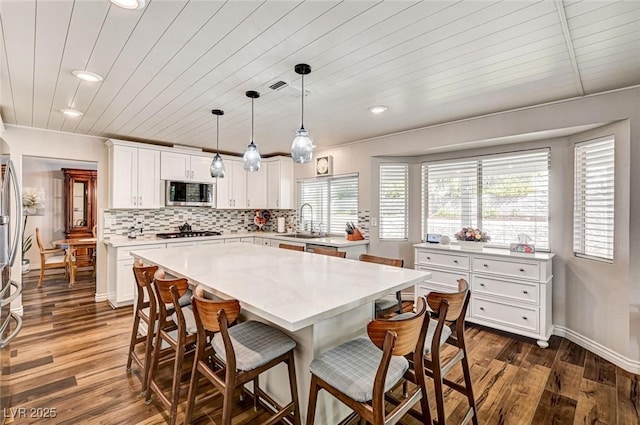 2036 Deer Springs Dr, Henderson, NV 89074 - kitchen with stainless steel microwave, a kitchen bar, recessed lighting, light countertops, and dark wood-type flooring