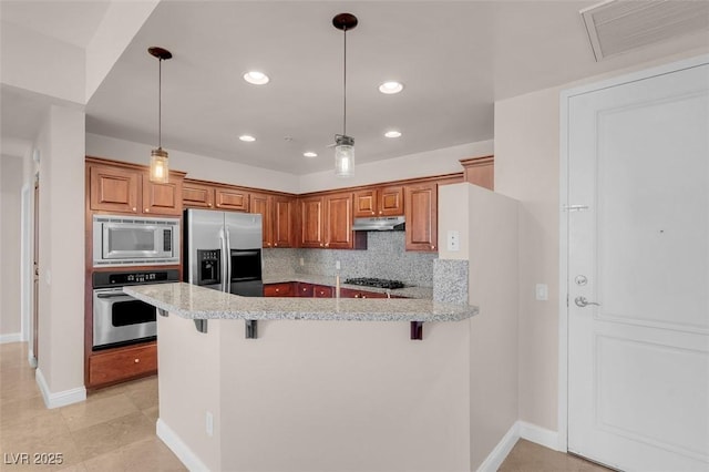 87 E Agate Ave Unit 403, Las Vegas, NV 89123 - kitchen with stainless steel appliances, under cabinet range hood, baseboards, a peninsula, and a kitchen breakfast bar