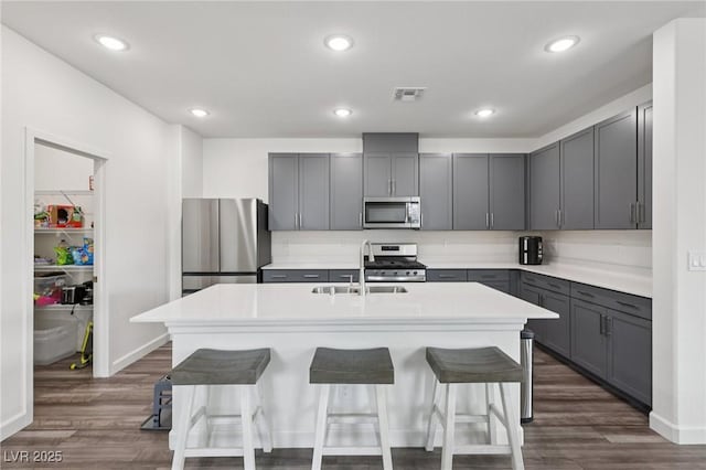 3024 River Brook Ct, Las Vegas, NV 89139 - kitchen featuring stainless steel appliances, a sink, gray cabinetry, a kitchen bar, and recessed lighting
