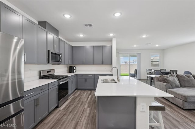 3024 River Brook Ct, Las Vegas, NV 89139 - kitchen featuring stainless steel appliances, a sink, gray cabinetry, open floor plan, and a kitchen breakfast bar