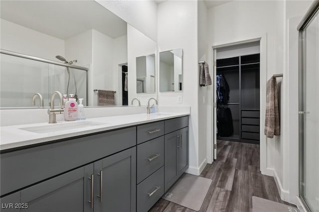 3024 River Brook Ct, Las Vegas, NV 89139 - bathroom with wood finished floors, a shower stall, double vanity, a walk in closet, and baseboards