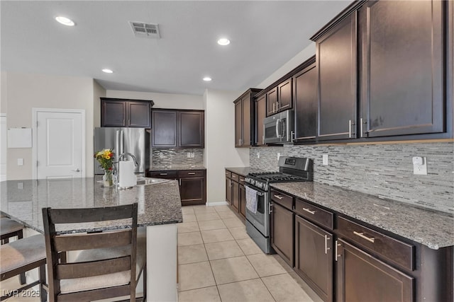 9950 Coyote Echo Ct, Las Vegas, NV 89166 - kitchen featuring stainless steel appliances, dark stone countertops, tasteful backsplash, light tile patterned floors, and recessed lighting