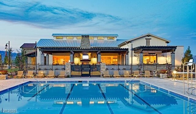 9950 Coyote Echo Ct, Las Vegas, NV 89166 - back of property featuring a community pool, a metal roof, and a patio area