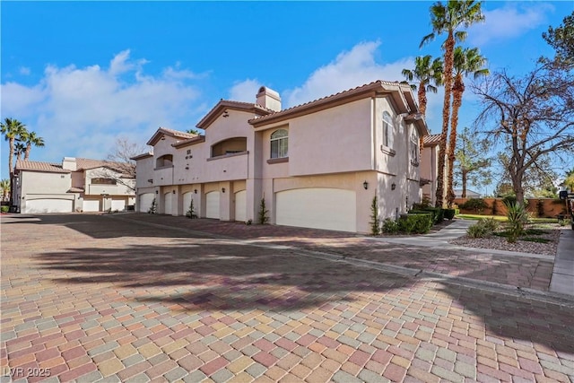 108 Lemon Glaze St Unit 202, Las Vegas, NV 89145 - rear view of property with an attached garage, a chimney, a tile roof, stucco siding, and decorative driveway