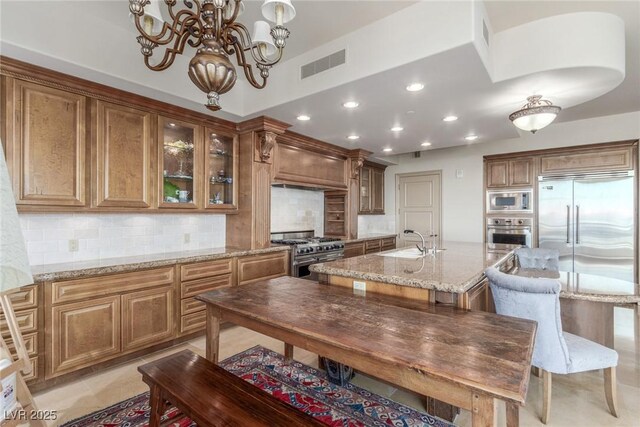 9101 Alta Dr Unit 203, Las Vegas, NV 89145 - kitchen with built in appliances, a sink, premium range hood, an island with sink, and decorative backsplash