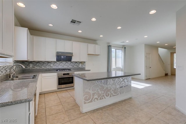 6442 Kobe Knoll Ct, Las Vegas, NV 89141 - kitchen featuring stainless steel oven, under cabinet range hood, backsplash, light tile patterned floors, and white cabinetry