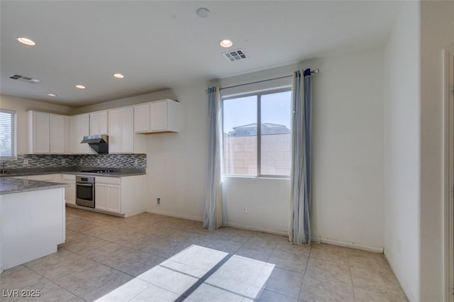 6442 Kobe Knoll Ct, Las Vegas, NV 89141 - kitchen featuring oven, decorative backsplash, white cabinets, under cabinet range hood, and light tile patterned flooring
