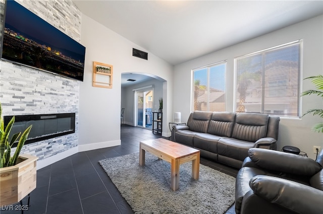 7288 Quarterhorse Ln, Las Vegas, NV 89148 - living room with arched walkways, lofted ceiling, a fireplace, and dark tile patterned flooring