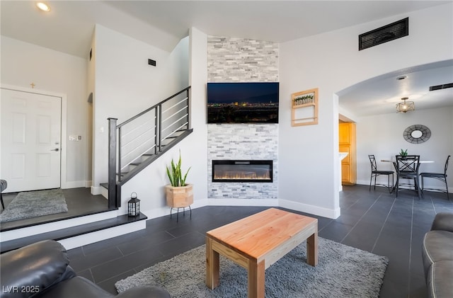 7288 Quarterhorse Ln, Las Vegas, NV 89148 - living area with a fireplace, stairway, dark tile patterned flooring, and arched walkways