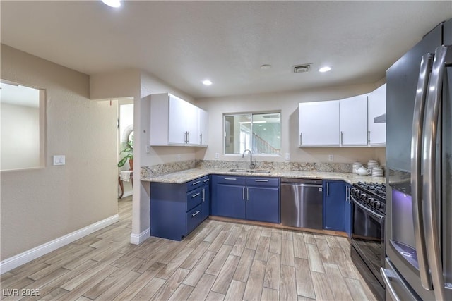 4428 Los Reyes Ct, Las Vegas, NV 89121 - kitchen featuring stainless steel appliances, a sink, blue cabinetry, light wood-style flooring, and white cabinetry