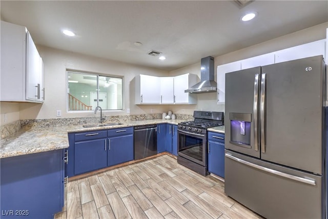 4428 Los Reyes Ct, Las Vegas, NV 89121 - kitchen with appliances with stainless steel finishes, wall chimney range hood, blue cabinets, a sink, and white cabinets