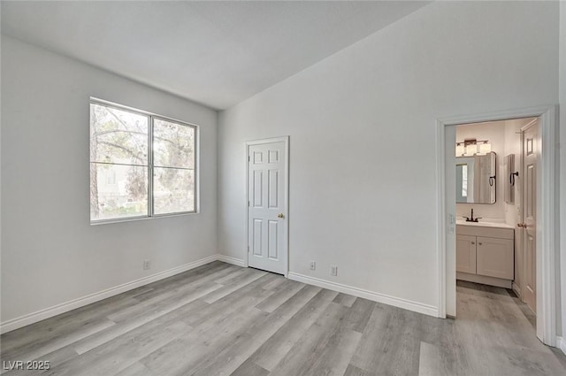 5155 W Tropicana Ave Unit 2095, Las Vegas, NV 89103 - unfurnished bedroom with light wood-style flooring, lofted ceiling, baseboards, and ensuite bathroom
