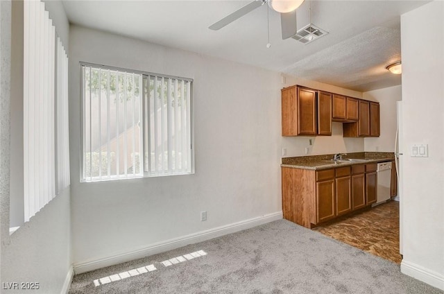 1846 N Decatur Blvd Unit 104, Las Vegas, NV 89108 - kitchen with white dishwasher, brown cabinetry, ceiling fan, and carpet floors