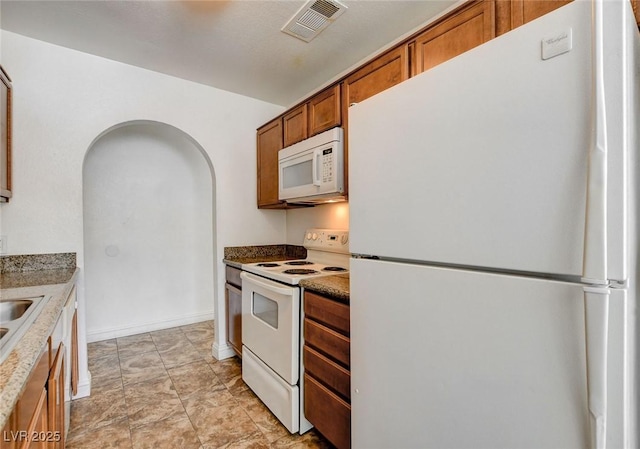 1846 N Decatur Blvd Unit 104, Las Vegas, NV 89108 - kitchen featuring white appliances, brown cabinets, and arched walkways