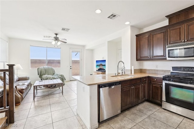 8341 Lower Trailhead Ave, Las Vegas, NV 89113 - kitchen featuring stainless steel appliances, a sink, open floor plan, light tile patterned floors, and dark brown cabinetry
