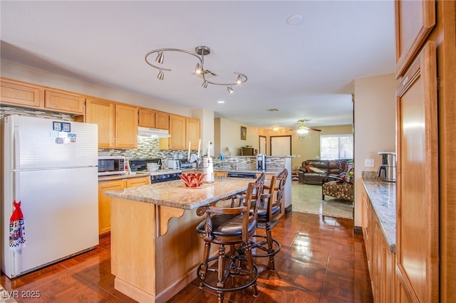 7801 Olympus Ave, Las Vegas, NV 89131 - kitchen featuring freestanding refrigerator, stainless steel microwave, electric range oven, under cabinet range hood, and open floor plan
