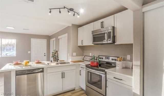 1820 Yale St, North Las Vegas, NV 89030 - kitchen featuring stainless steel appliances, a sink, a peninsula, light countertops, and white cabinets