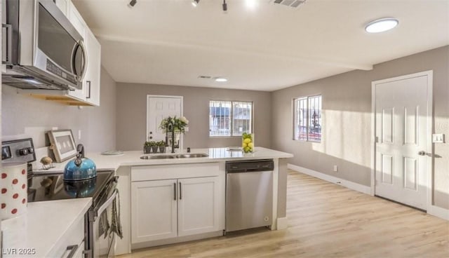 1820 Yale St, North Las Vegas, NV 89030 - kitchen featuring appliances with stainless steel finishes, a peninsula, a sink, light wood-type flooring, and light countertops