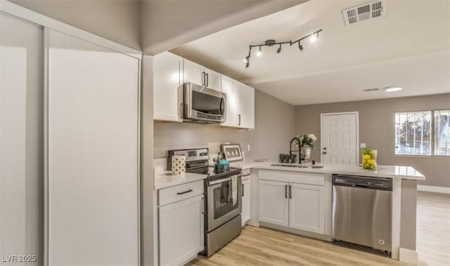 1820 Yale St, North Las Vegas, NV 89030 - kitchen with appliances with stainless steel finishes, a sink, a peninsula, light wood finished floors, and light countertops