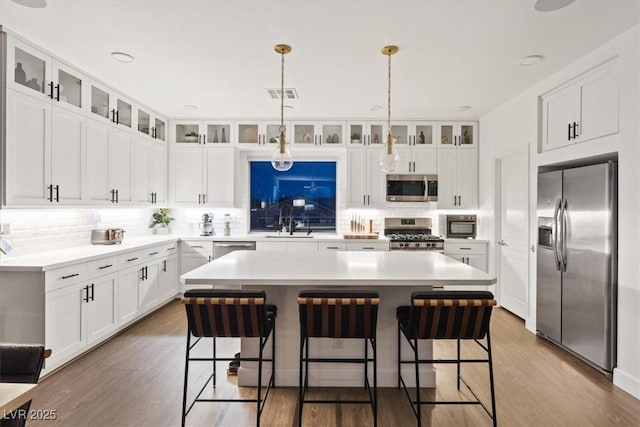 8055 Haywood Estate Ave, Las Vegas, NV 89113 - kitchen with appliances with stainless steel finishes, a breakfast bar area, a center island, and tasteful backsplash