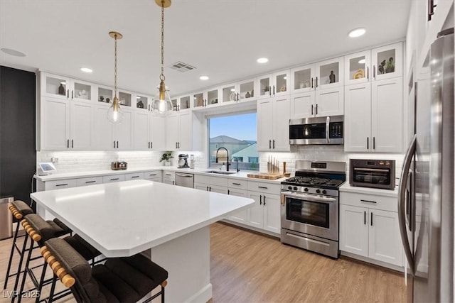8055 Haywood Estate Ave, Las Vegas, NV 89113 - kitchen with appliances with stainless steel finishes, a kitchen breakfast bar, decorative backsplash, a kitchen island, and recessed lighting