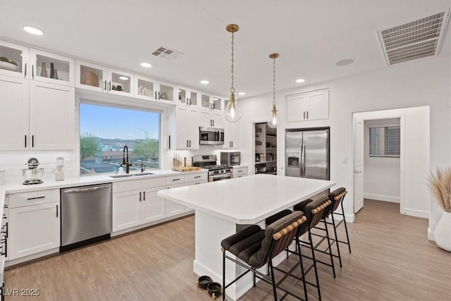 8055 Haywood Estate Ave, Las Vegas, NV 89113 - kitchen with stainless steel appliances, a breakfast bar area, light wood-style flooring, white cabinetry, and recessed lighting