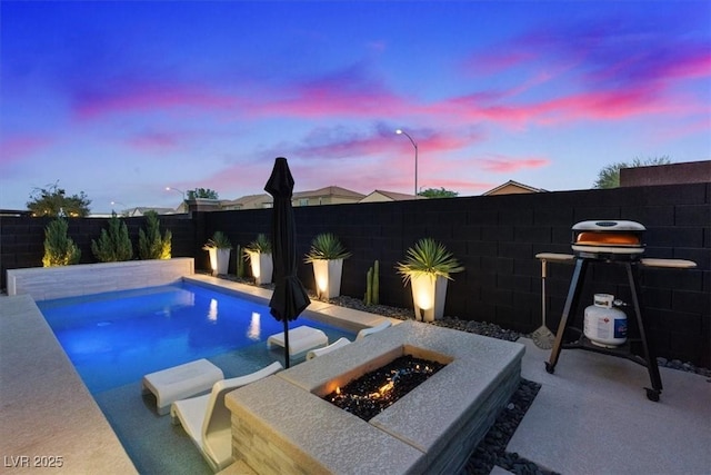 8055 Haywood Estate Ave, Las Vegas, NV 89113 - pool at dusk featuring an outdoor fire pit, a fenced backyard, a patio, and grilling area