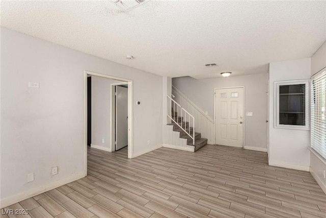 1704 Kismet Cir, Las Vegas, NV 89108 - foyer entrance featuring light wood-style floors, stairs, a textured ceiling, and baseboards