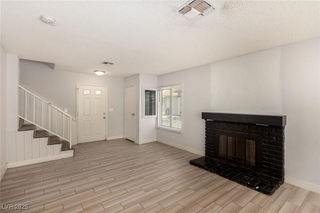 1704 Kismet Cir, Las Vegas, NV 89108 - unfurnished living room with a textured ceiling, wood finished floors, stairway, baseboards, and a brick fireplace