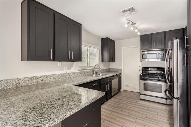 1704 Kismet Cir, Las Vegas, NV 89108 - kitchen with appliances with stainless steel finishes, a sink, light stone countertops, and light wood-style floors
