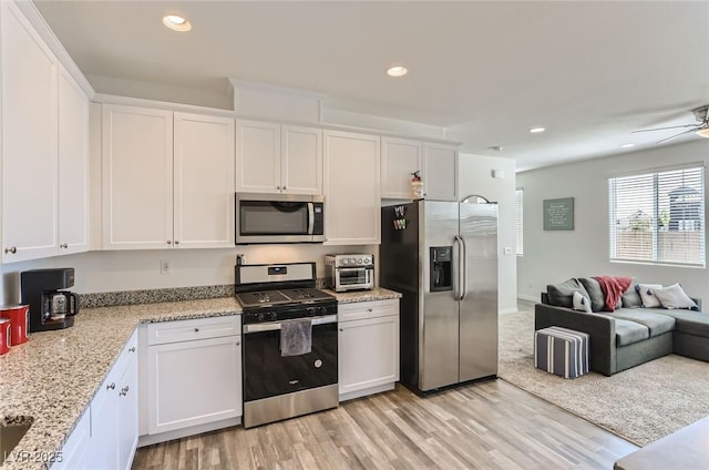 1611 Prairie Fields Ct, Las Vegas, NV 89115 - kitchen featuring stainless steel appliances, open floor plan, white cabinets, light wood-style flooring, and recessed lighting